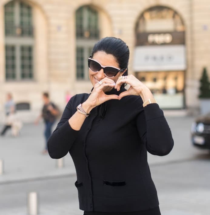 Patrícia Garboni fazendo um coração com as mãos em uma rua de Paris